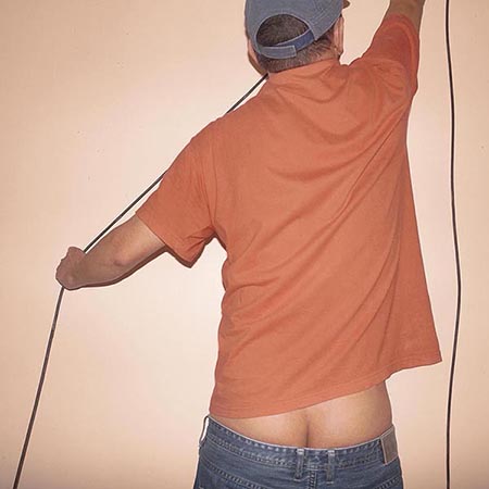 Electrician's assistant with his pants sagging and butt crack exposed preparing wire to attach to the wall.